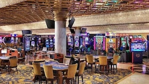 Ein Casino-Innenraum mit Spieltischen, Stühlen und Spielautomaten.