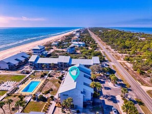 Eine Vogelperspektive eines Küstenhotels mit Schwimmbad, Strandzugang und einer langen Straße, die zum Meer führt.