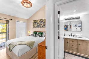 A bedroom with a bed, a bedside table, a lamp, and a window. - Steps to the Beach|Pool & Gulf Views| sleeps 6 (Saint George Island)