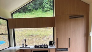 Una cocina moderna con armarios de madera, horno empotrado, lavabo y cafetera.
