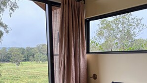 Un dormitorio con un ventanal grande, una cama con ropa de cama azul y una lámpara en la mesita de noche.