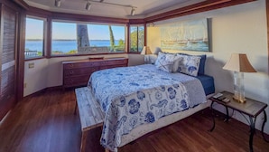 A bedroom with a large bed, wooden dresser, and a view of the sea. - The Seagates Private Coastal Retreat | Coos Bay (Coos Bay)
