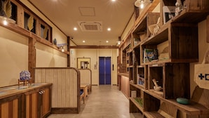 A hallway with wooden shelves, a blue door, and a bench.