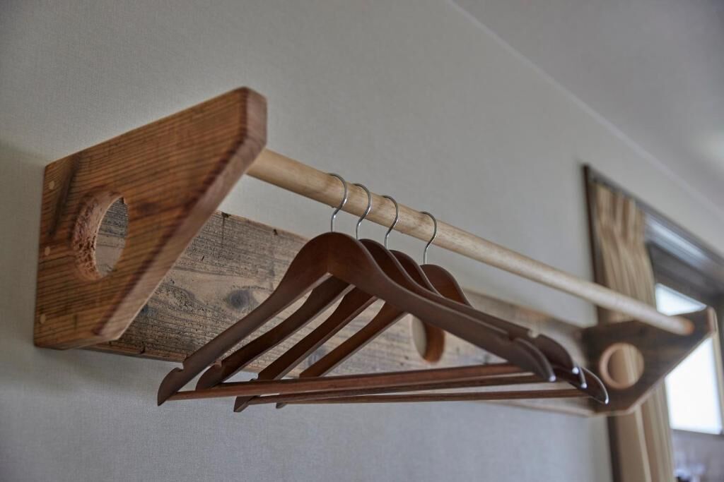 A wooden coat rack with multiple hangers and a coat hook.