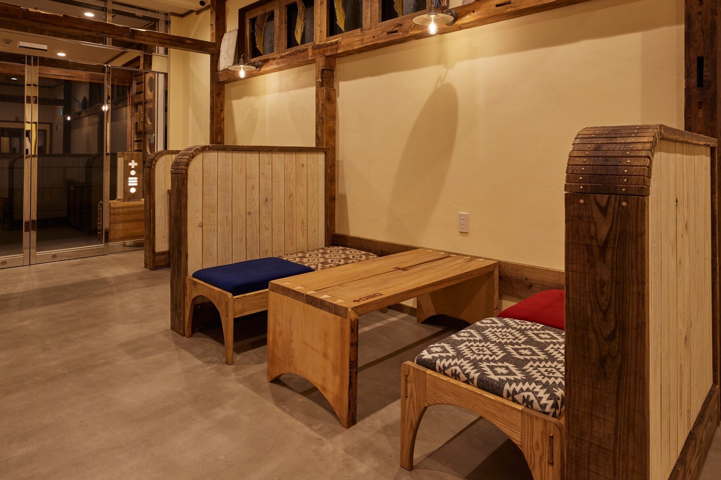 Una habitación de madera con una banca, una mesa y una cama.