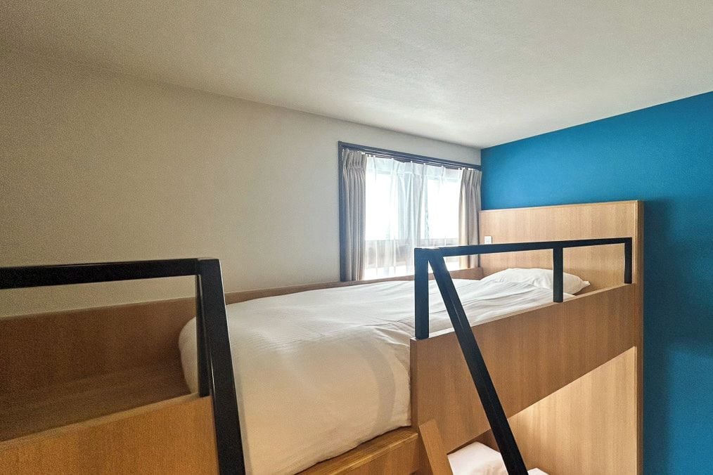 A single room with a bunk bed and a window with curtains.