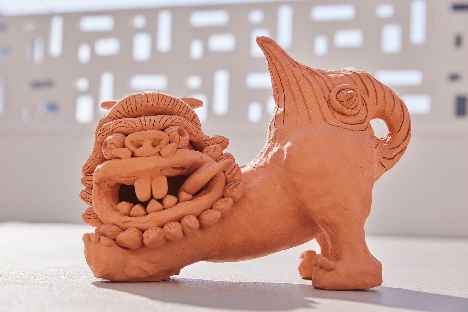 Une sculpture en terre cuite représentant un lion à la gueule ouverte, avec une figure humaine à l’intérieur.