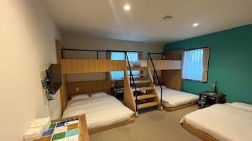 A room with bunk beds, a desk with a computer, and a window with curtains.