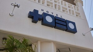 A hotel sign with a plus symbol and the word 'HOTEL' on a building facade.