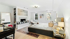 Een moderne slaapkamer met een groot bed, een open haard, een bureau en een boekenkast.