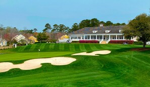 Um campo de golfe com um clube, valas de areia e gramados bem cuidados.