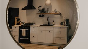 A kitchen with white cabinets, a black stove, a sink, and a hanging light fixture. - Parkway Grove Cabins 1 Bedroom with Private Hot Tub and Spa Shower (Miranda)