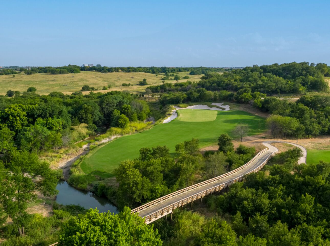 Un ponte sopra un fiume, con un campo da golf sullo sfondo.