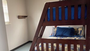 A bunk bed with a wooden frame and a blue and yellow quilt. There is a small shelf on the wall and a window with blinds. - Cozy 3-bedroom house in delightful LaFollette with AC (LaFollette)