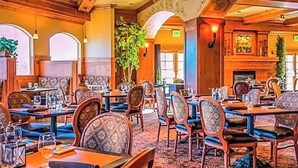 A restaurant with wooden furniture, large windows, and a fireplace.