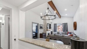 A modern kitchen with a granite countertop, a hanging chandelier, and a large island.