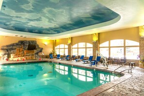An indoor swimming pool with a stone wall and a ceiling with a cloud design. - Zermatt Villa 1 Bedroom 1 Bath Full Kitchen with Resort Amenities - 3014-1 (Midway)