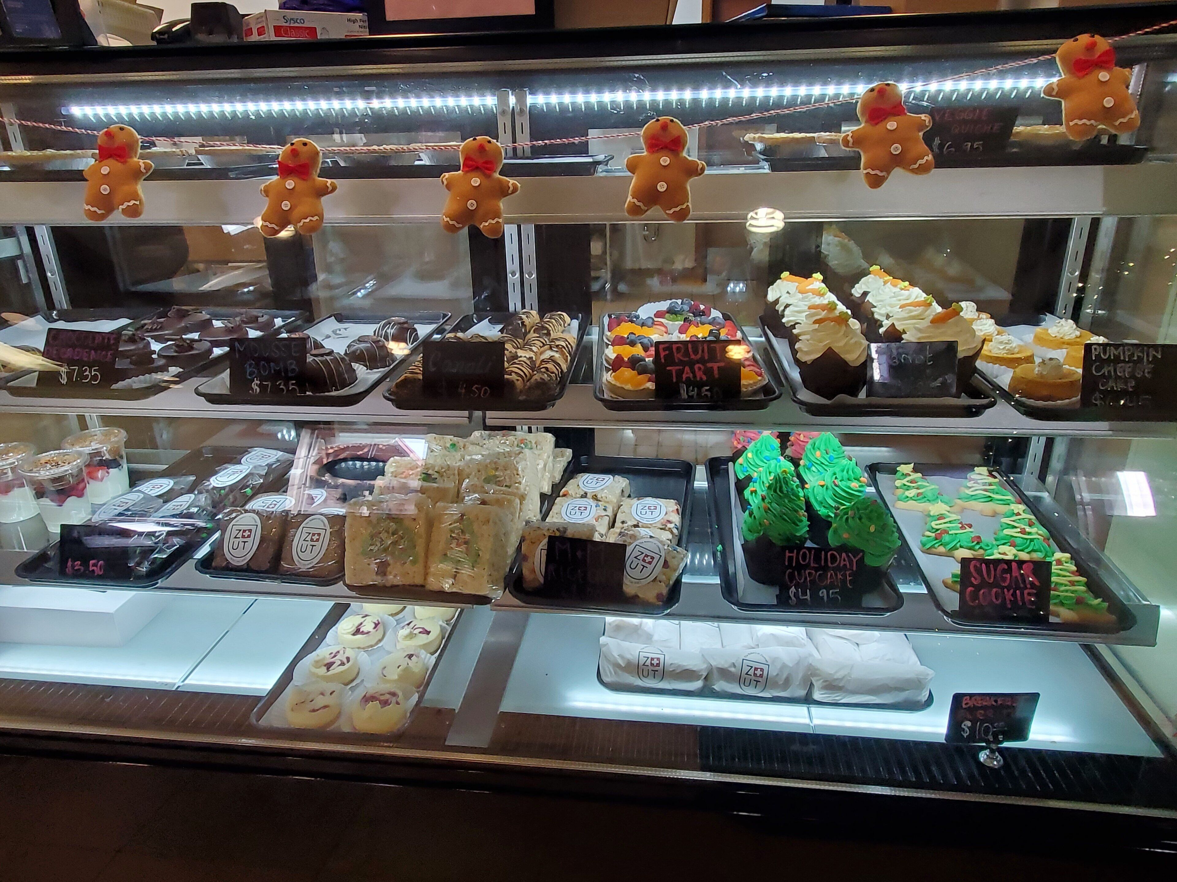 A bakery display case with various baked goods, including gingerbread men, chocolate desserts, and holiday-themed treats.