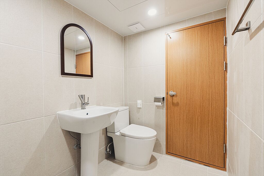 A bathroom with a white sink, a toilet, and a wooden door.