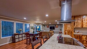 A spacious kitchen with a dining area, wooden cabinets, and a large island with a stove. - The Guest House & Cottage at Seagate- Coos Bay, OR (Coos Bay)