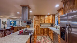 A modern kitchen with wooden cabinets, a stainless steel refrigerator, and a central island with a stove. - The Guest House & Cottage at Seagate- Coos Bay, OR (Coos Bay)