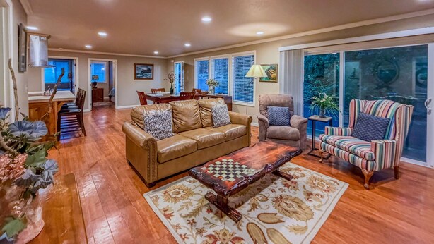 A spacious living room with a leather sofa, a patterned rug, and a chess table. - The Guest House & Cottage at Seagate- Coos Bay, OR (Coos Bay)