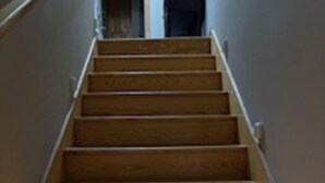 A wooden staircase with a handrail on the left, leading upwards. - The Ranch Luxury Experiences (Gadsden)