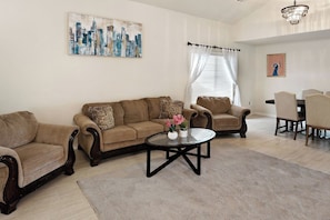 A living room with a sofa set, a coffee table, and a dining area with chairs.