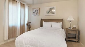 A neatly made bed with a wooden headboard, a bedside table with a lamp, and two framed artworks on the wall. - 3BR Casa Grande Home with Private Pool and Sofa Sleeper (Casa Grande)