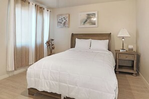 A neatly made bed with a wooden headboard, a bedside table with a lamp, and two framed artworks on the wall. - 3BR Casa Grande Home with Private Pool and Sofa Sleeper (Casa Grande)