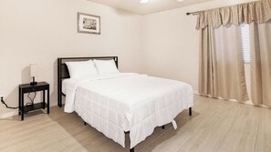 A bedroom with a bed, a nightstand, a lamp, a picture on the wall, and a window with curtains. - 3BR Casa Grande Home with Private Pool and Sofa Sleeper (Casa Grande)