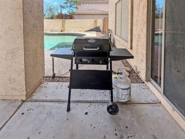 A barbecue grill with a gas tank and a table on a patio. - 3BR Casa Grande Home with Private Pool and Sofa Sleeper (Casa Grande)