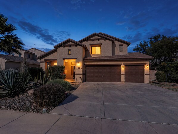 A two-story house with a garage, a driveway, and a well-maintained garden with cacti and shrubs. - 3BR Casa Grande Home with Private Pool and Sofa Sleeper (Casa Grande)