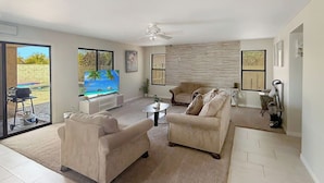 A spacious living room with a large TV, comfortable seating, and a view of the outdoors. - 3BR Casa Grande Home with Private Pool and Sofa Sleeper (Casa Grande)