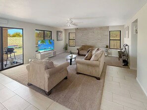 A spacious living room with a large TV, comfortable seating, and a view of the outdoors. - 3BR Casa Grande Home with Private Pool and Sofa Sleeper (Casa Grande)