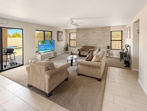 A spacious living room with a flat-screen TV, two sofas, a coffee table, and a ceiling fan. - 3BR Casa Grande Home with Private Pool and Sofa Sleeper (Casa Grande)
