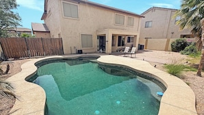 A swimming pool with a curved edge, surrounded by a patio area with chairs and a wooden fence. - 3BR Casa Grande Home with Private Pool and Sofa Sleeper (Casa Grande)