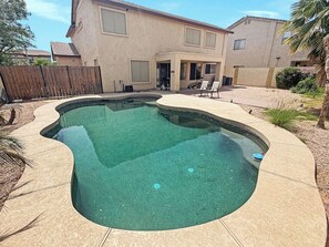 A swimming pool with a curved edge, surrounded by a patio area with chairs and a wooden fence. - 3BR Casa Grande Home with Private Pool and Sofa Sleeper (Casa Grande)