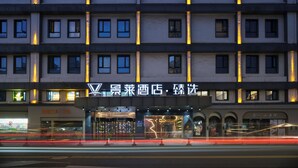 A multi-story hotel with a modern facade, illuminated windows, and a prominent entrance with a sign. - Jinglai Hotel · Curated Shanghai Xujiahui Jiaotong University Branch (Shanghai)