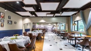 A restaurant with round tables, brown leather chairs, and a view of a cityscape through large windows. - Jinglai Hotel · Curated Shanghai Xujiahui Jiaotong University Branch (Shanghai)
