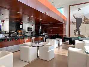 Un espace de détente moderne avec des canapés blancs, une table de billard et un bar décoré pour Noël.