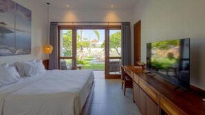 A hotel room with a bed, a desk, a television, and a view of the outdoors. - Braya Living (Denpasar)