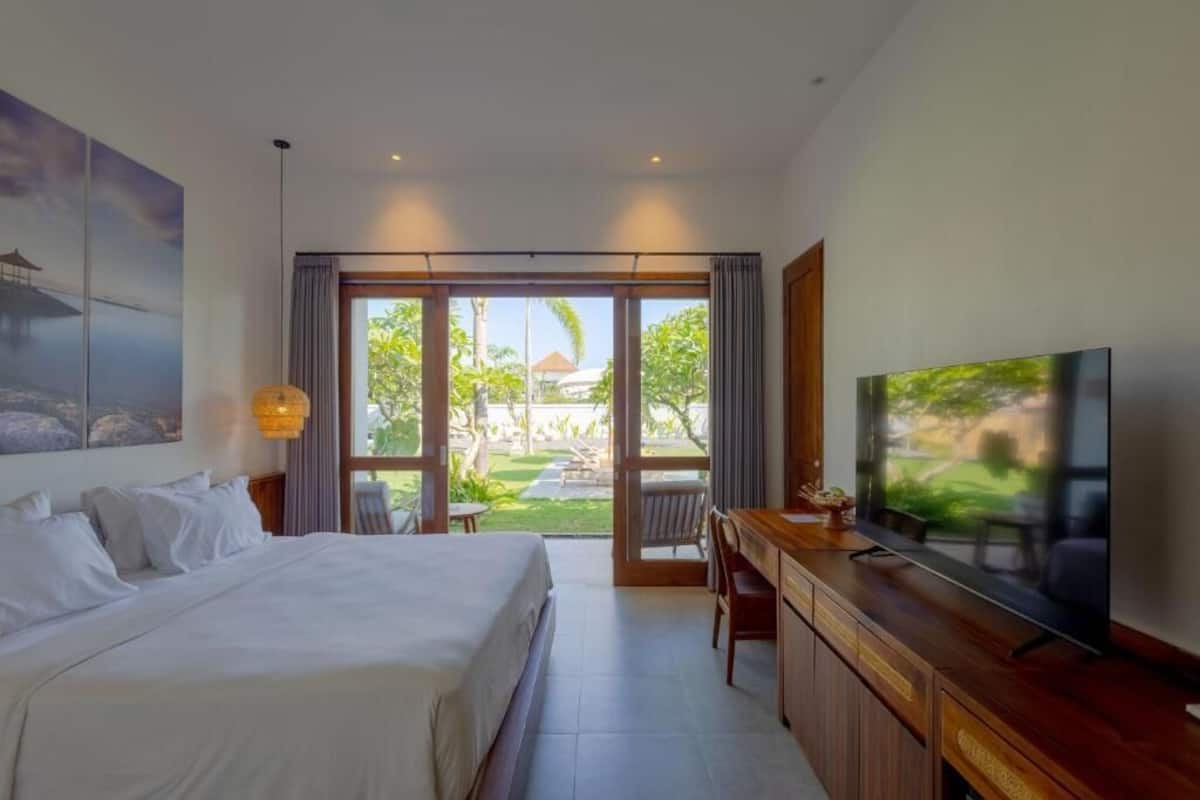 Ein Hotelzimmer mit Bett, Schreibtisch, Fernseher und Blick ins Freie.