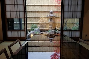 A traditional Japanese room with tatami flooring, a low table, and a view of a stone water feature through a shoji screen. - KONJAKUSO Osaka Tsuruhashi "KAKUJU" (Osaka)