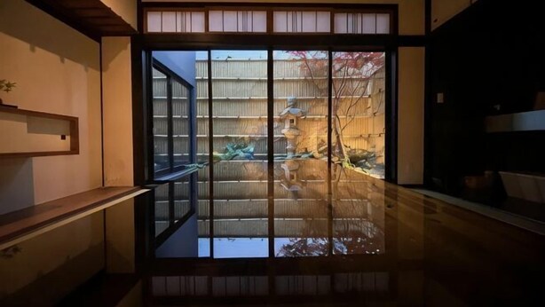 Une pièce de style japonais traditionnel, avec des portes coulissantes, un plancher en bois et une vue sur un jardin.