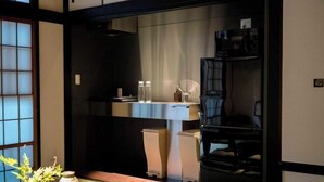 Une pièce de style japonais traditionnel, avec un sol recouvert de tatamis, une petite table sur laquelle est posé un vase, et une porte coulissante.