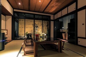 Et traditionelt japansk interiør med tatamimåtter, et lavt træbord og skydedøre til en have.