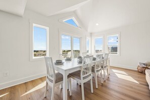 A bright dining area with a large table and chairs, large windows with a view, and a skylight.
