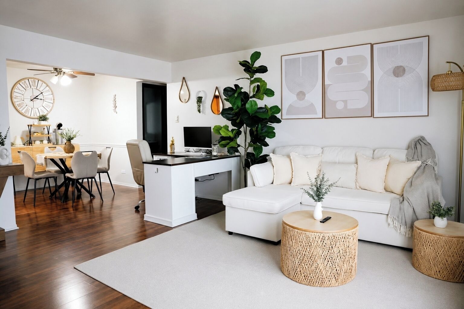 A modern living room with a white sofa, a dining area with a round table, and a large plant.