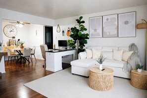 Un saló modern amb un sofà blanc, una zona de dinar amb una taula rodona i una planta gran.